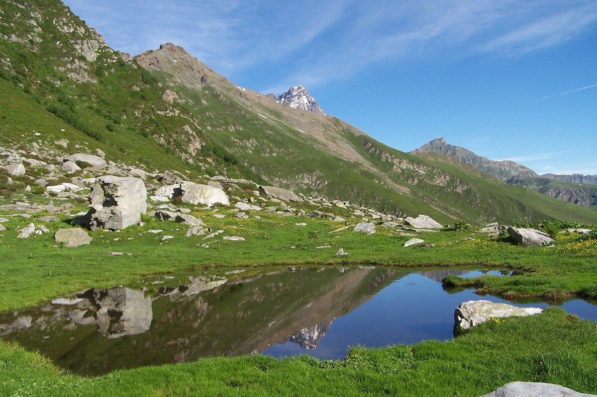 un lago alpino in primo piano, sullo sfondo il Monviso che si riflette anche nelle acque del lago