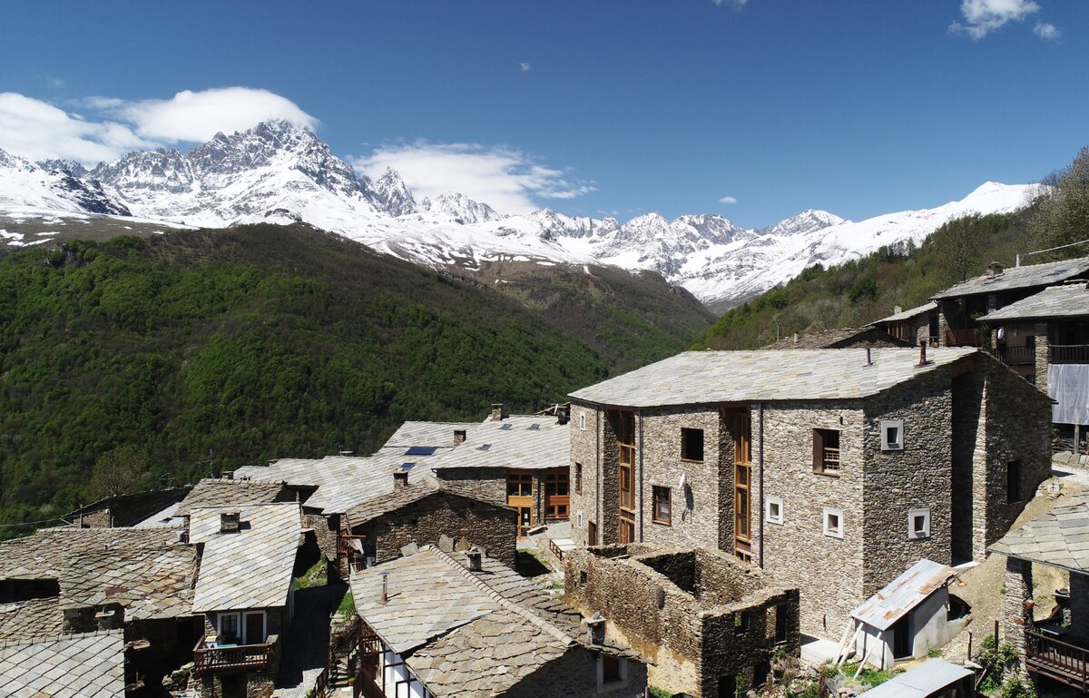 una borgata di Ostana, dalla caratteristica architettura in pietra, con il Monviso sullo sfondo