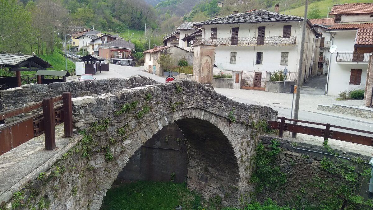 in primo piano l'antico ponte sul torrente, intorno le abitazioni del paese