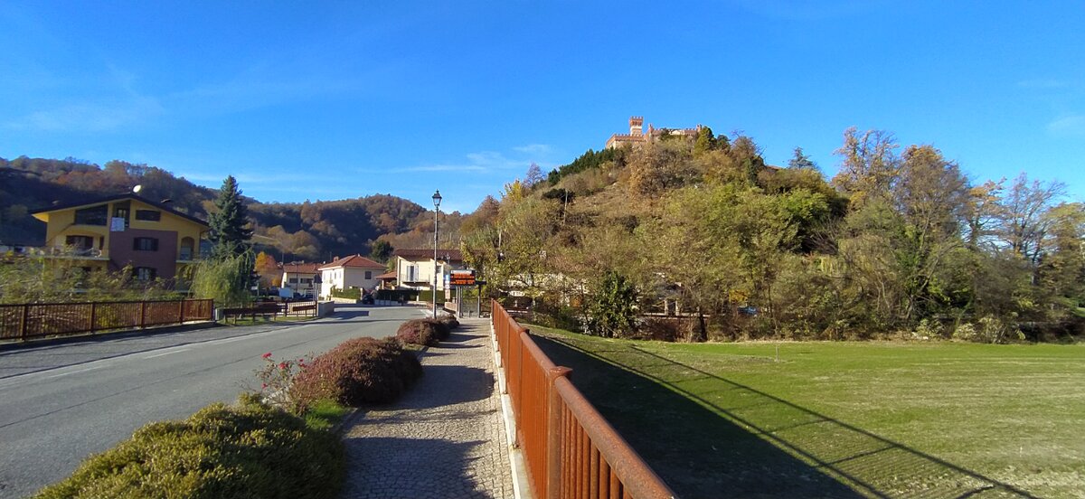 in primo piano la strada di accesso al paese, sullo sfondo in alto a destra si vede il castello che domina l'abitato