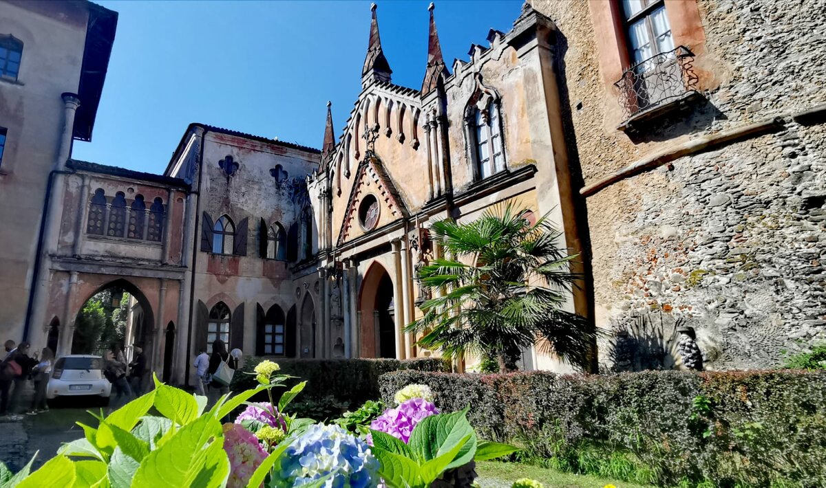 Veduta del cortile del Castello di Envie: in primo piano fiori, sullo sfondo l'architettura neogotica del palazzo