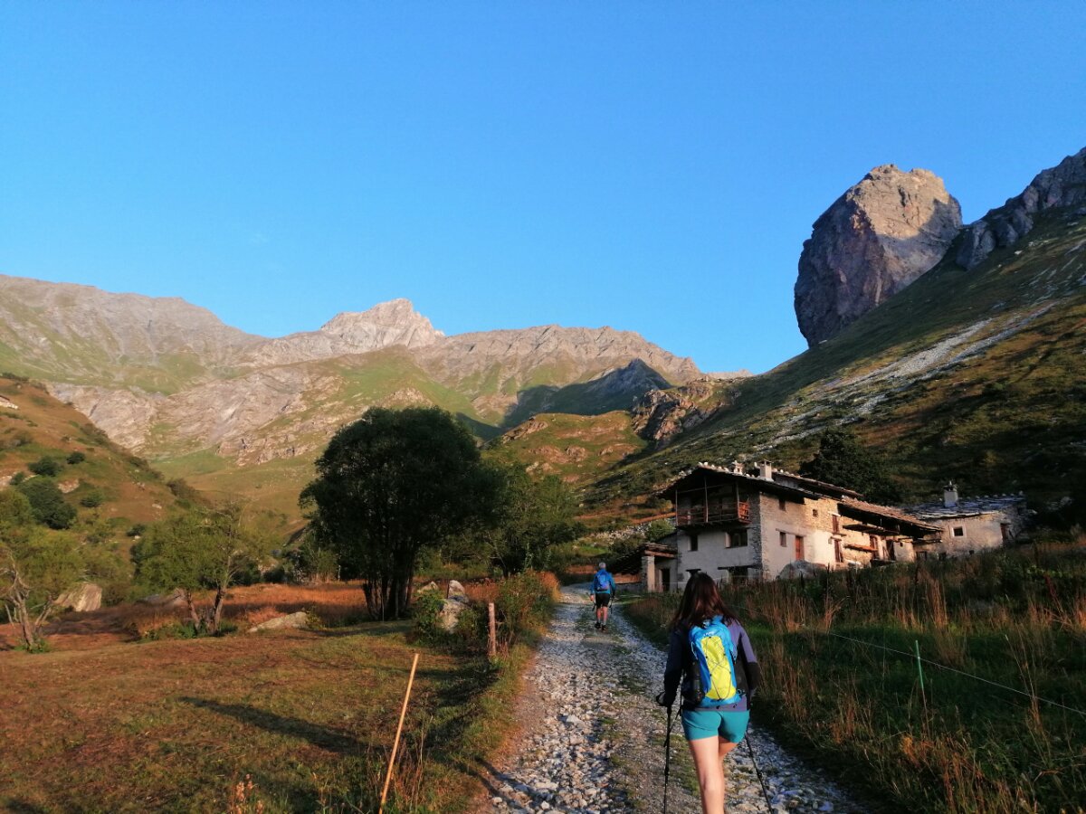 due escursionisti di spalle, a breve distanza tra loro, camminano su un sentiero che va verso l'alta valle Varaita, nel territorio di Bellino