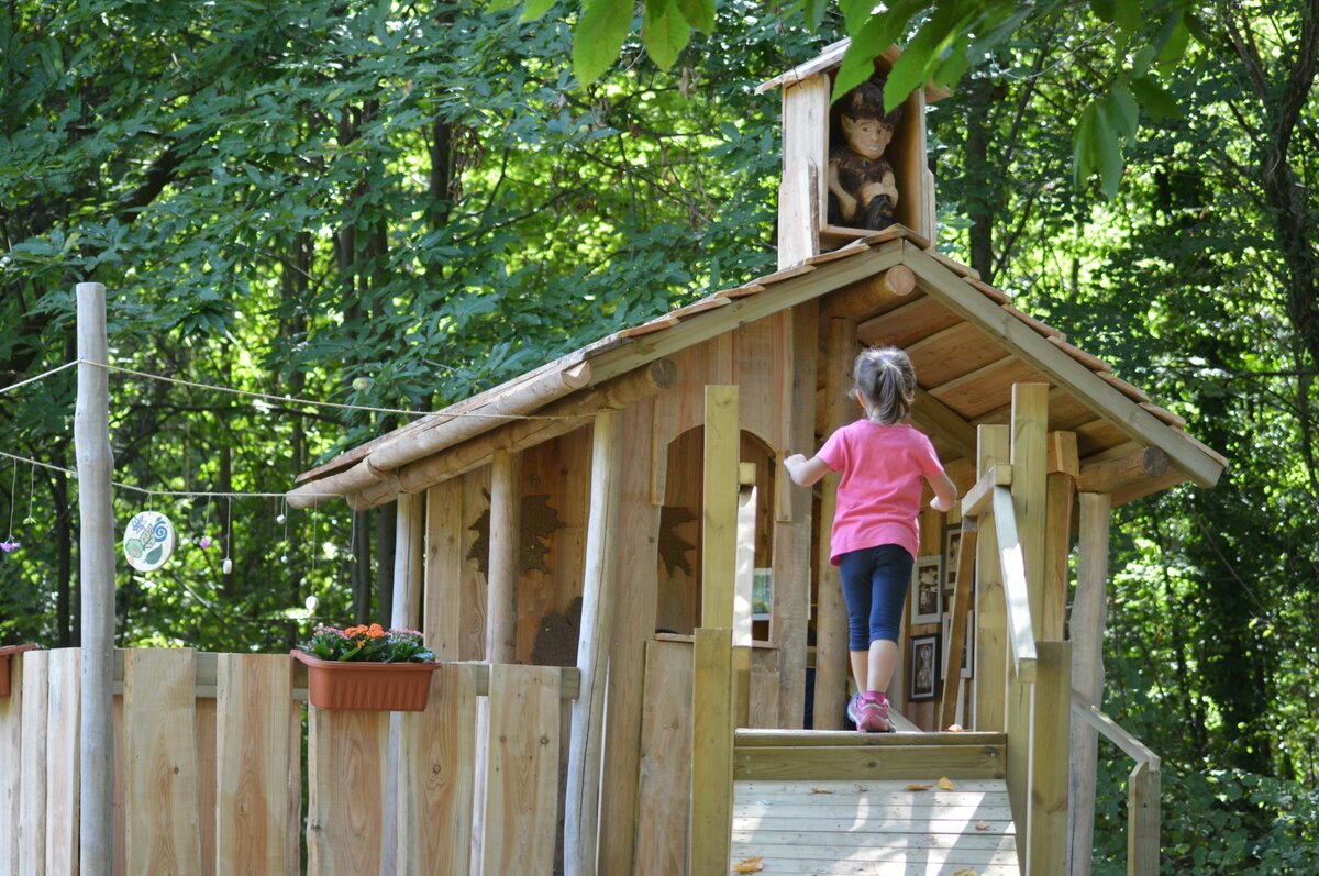 una bambina di spalle sta entrando in una casetta di legno